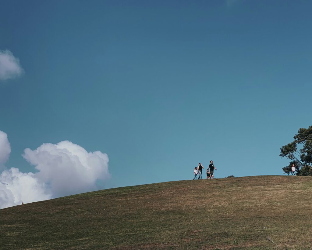 Gyerekek csoportja nyári táborban, szervezett program keretében játszanak a szabadban, miközben a táborvezető irányítja a napi programot.